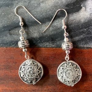 NWOT silver toned earrings.  2-1/2” drop, stylized sun design